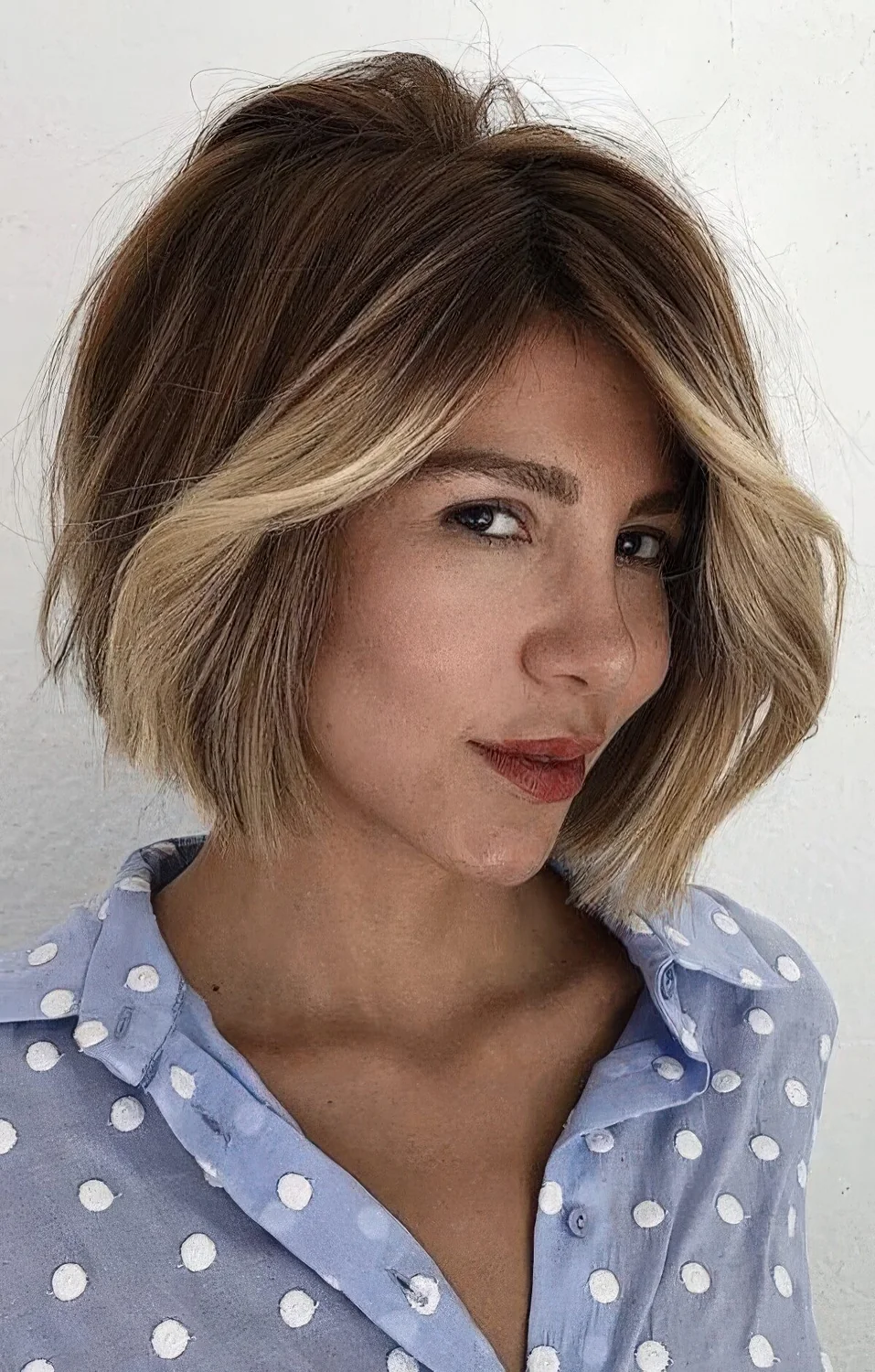 Jaw-length dark brunette bob with a blonde money piece and a lot of volume.