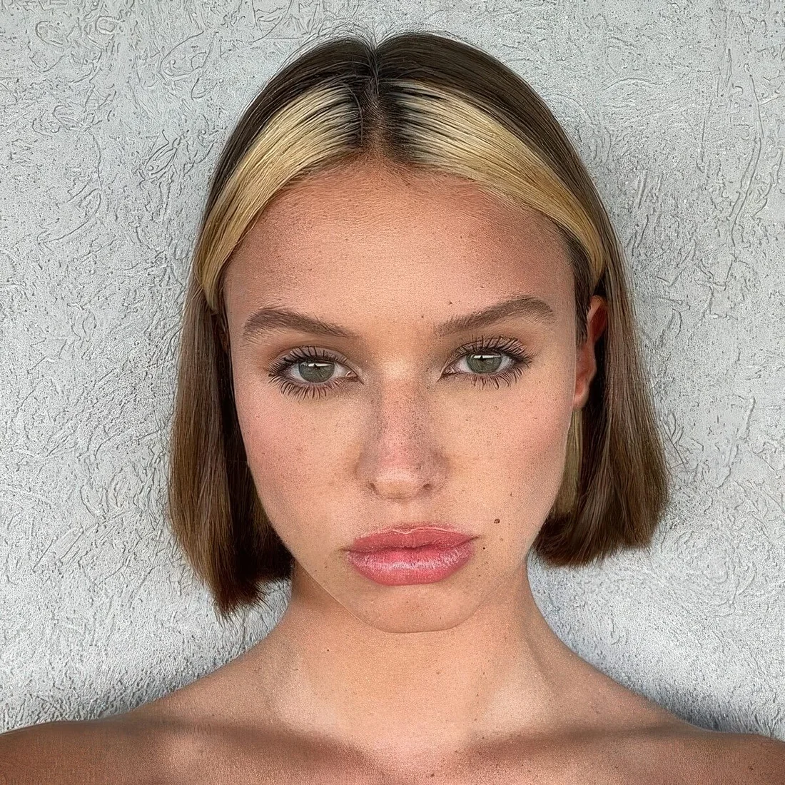 Short brunette bob with a blonde money piece to highlight and light up the eyes.