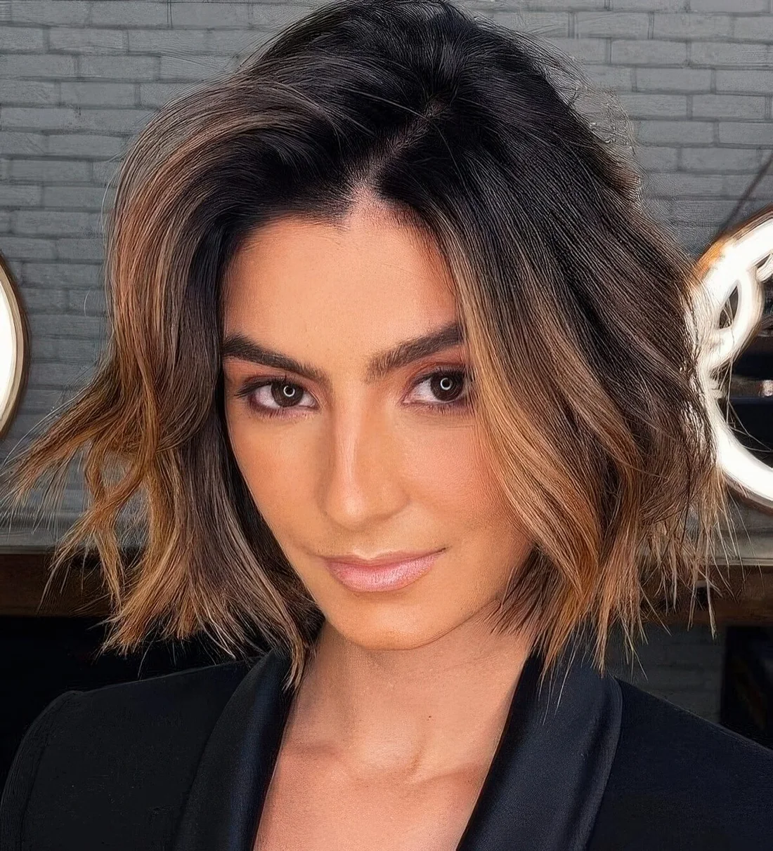 Short bob with a black root, caramel balayage including a money piece and a bit of waves for more elegance.