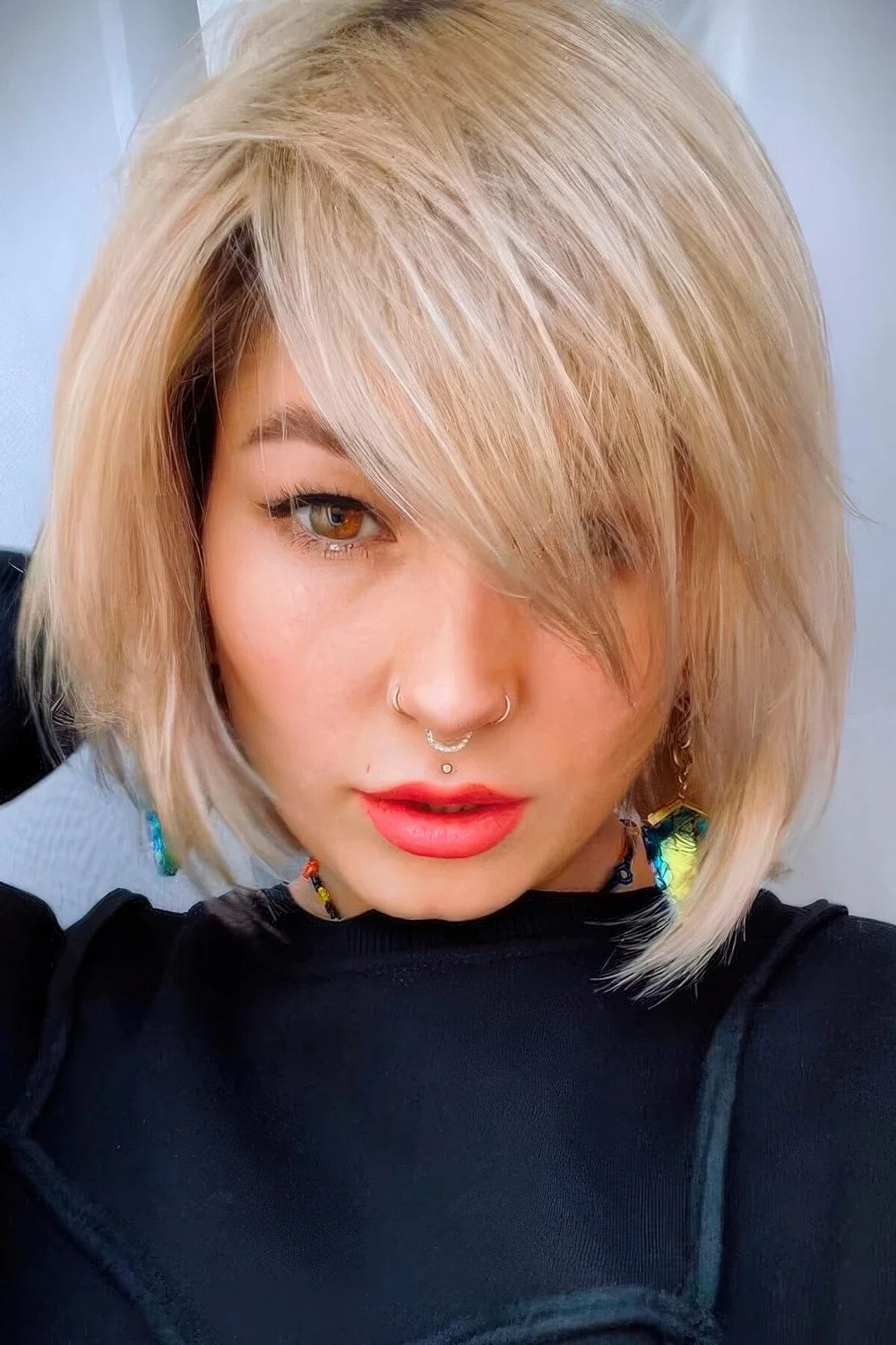 Chin-length creamy blonde bob with side bangs and plenty of movement and texture.