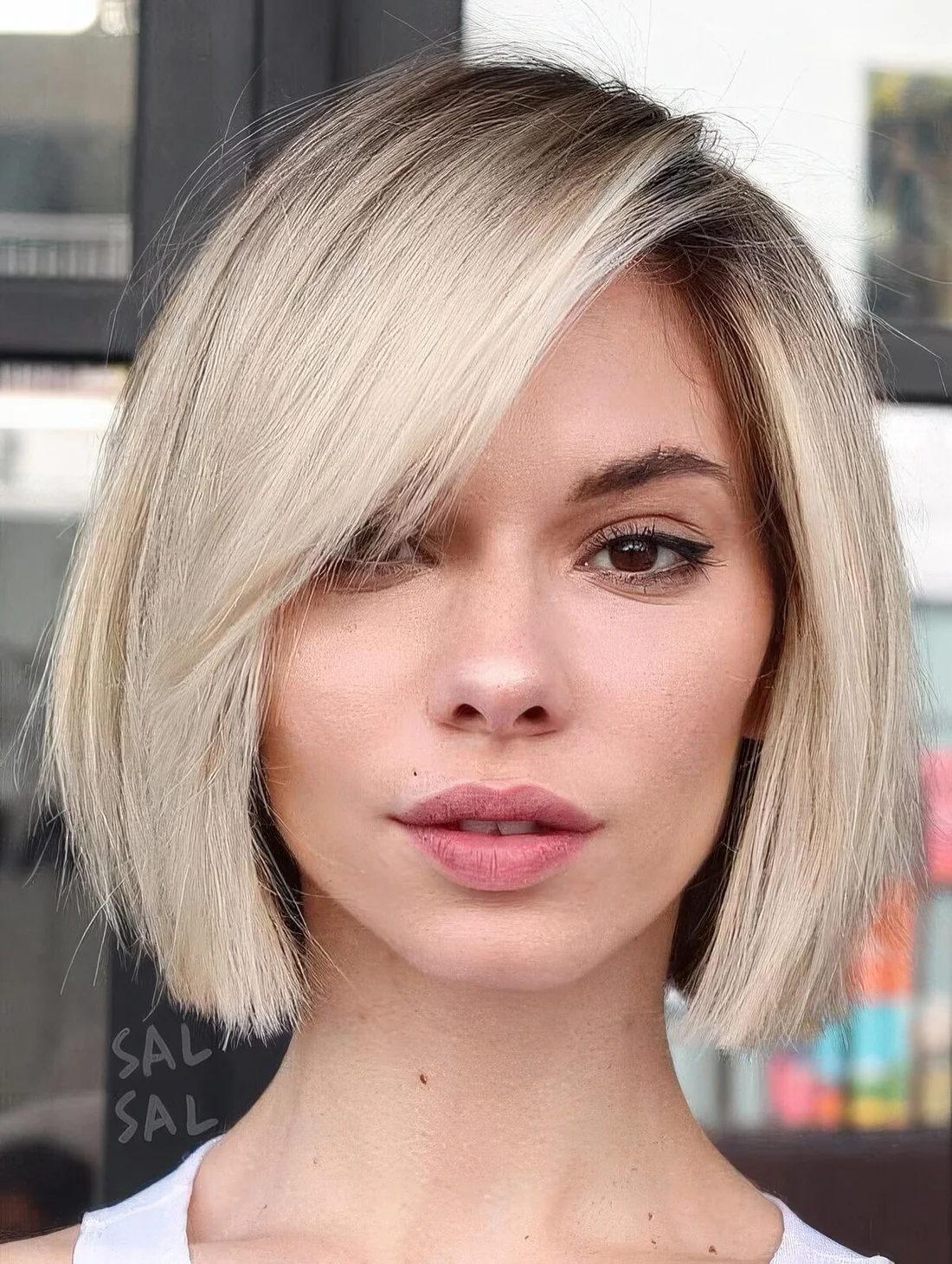 Blonde midi bob with side bangs and a darker root.
