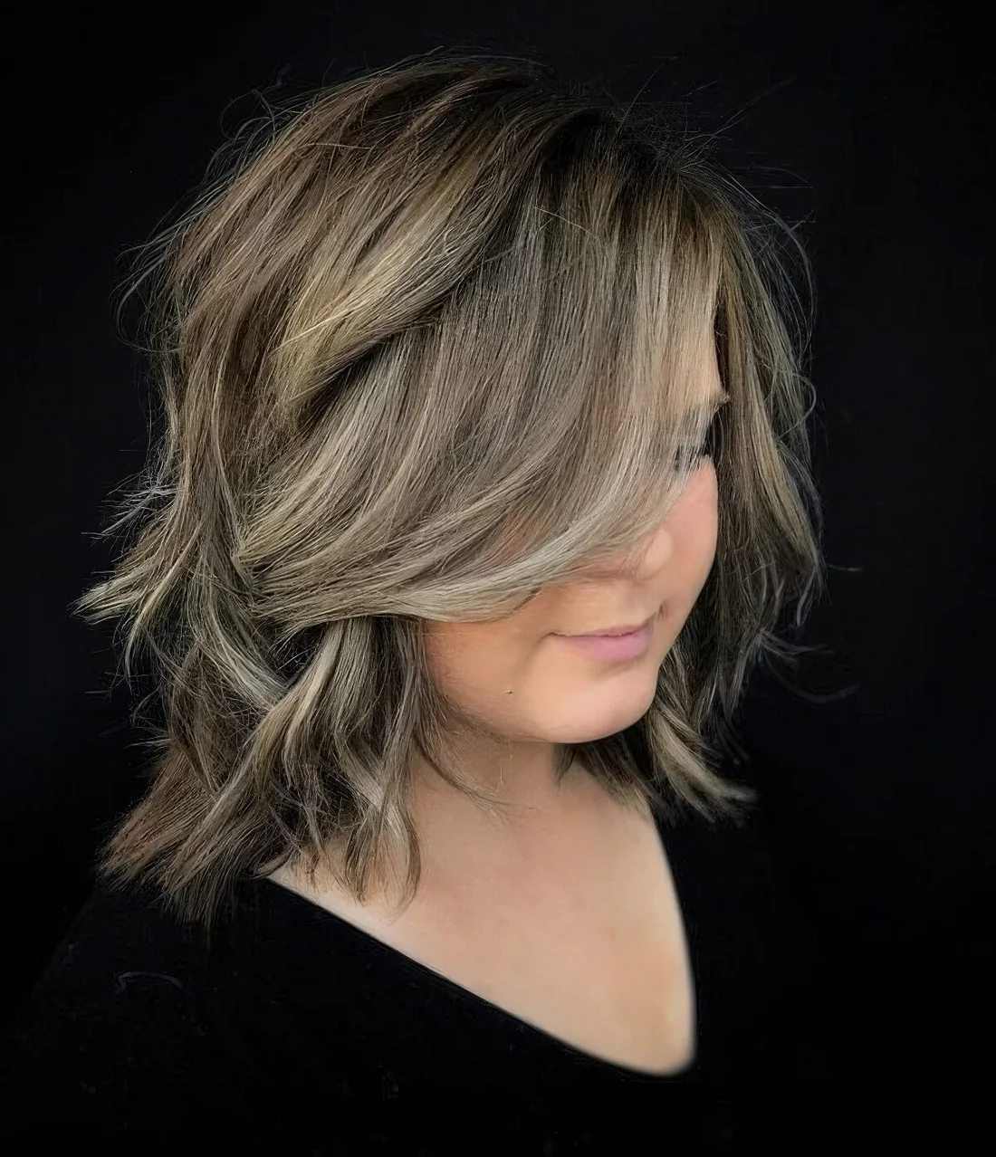 Long bob with blonde balayage and side bangs.
