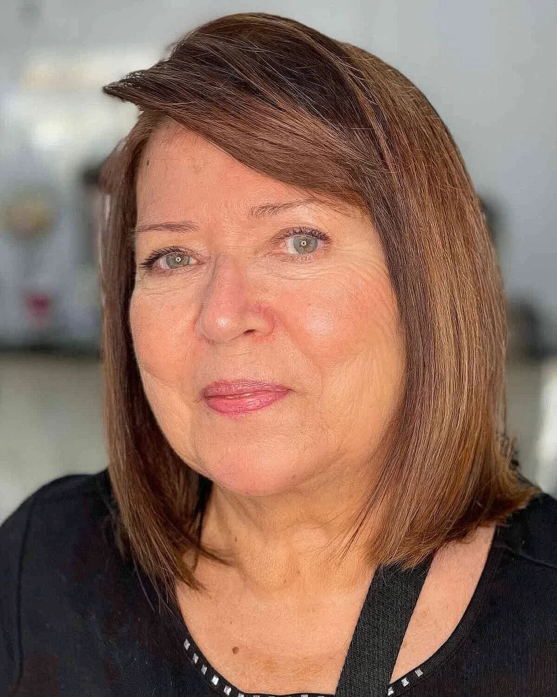 Sleek brown bob with caramel balayage and side bangs.