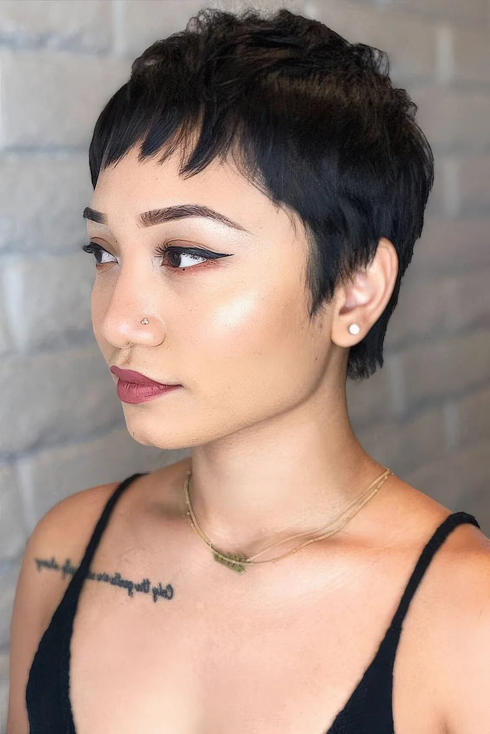Black pixie cut with wispy bangs and a bit of messy waves.