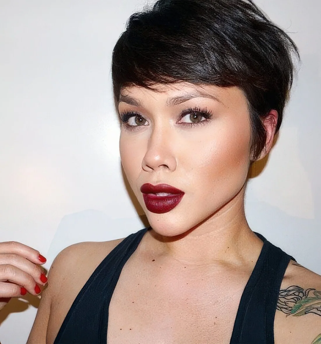Chic and shiny black pixie haircut with long side bangs and texture.
