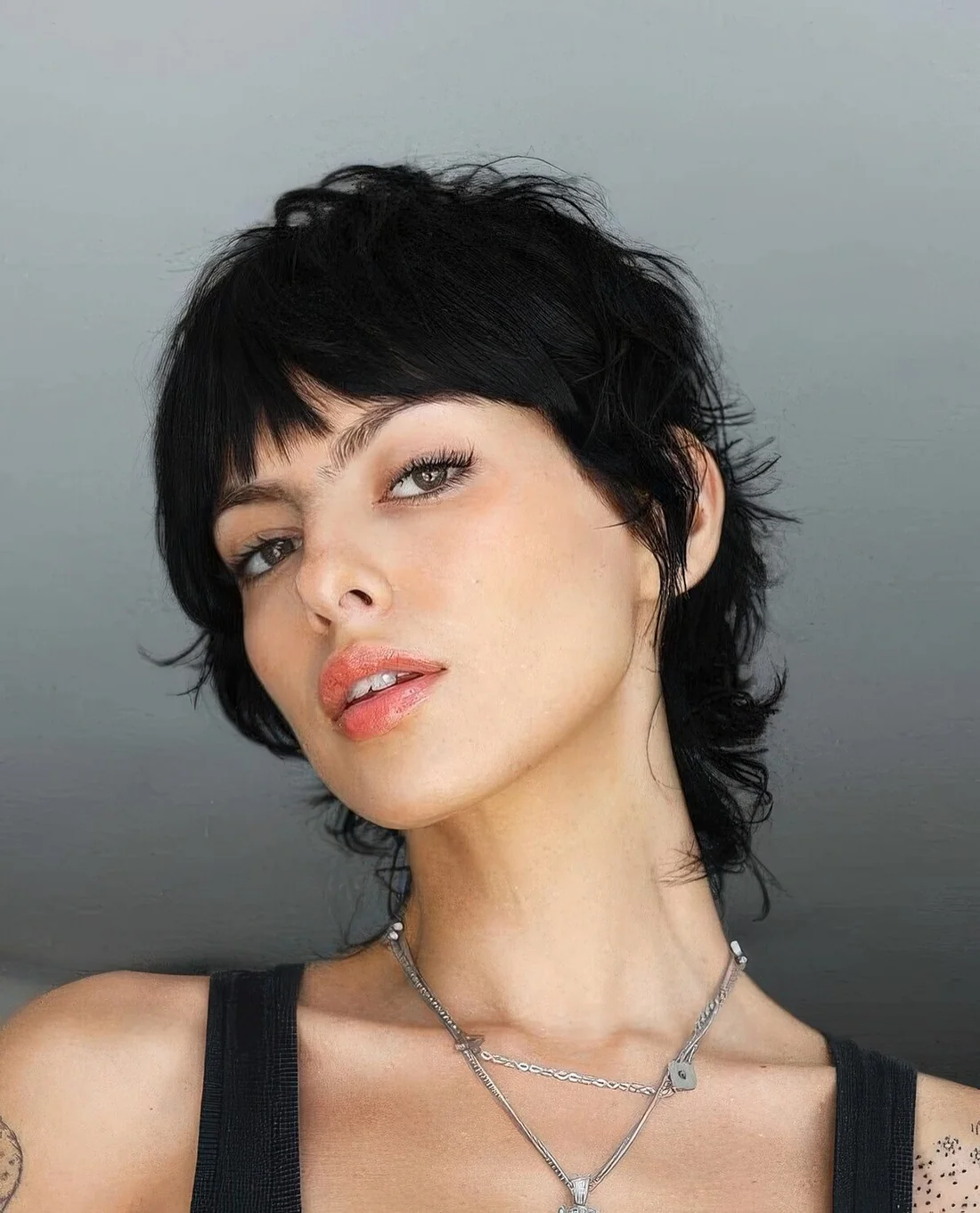 Short black mullet with bangs, waves and a lot of dimension.