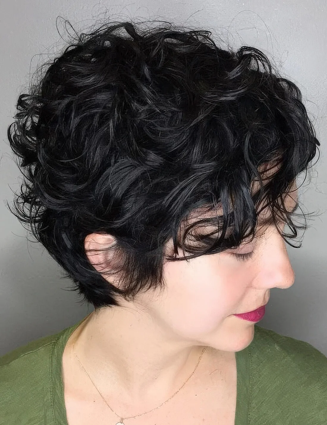 Delightful long black wavy pixie haircut with messy wavy bangs.