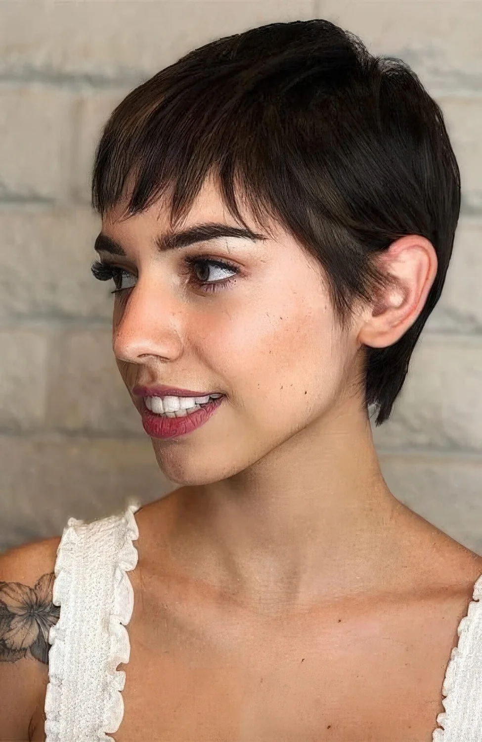 Long black pixie cut with wispy bangs and straight hair.