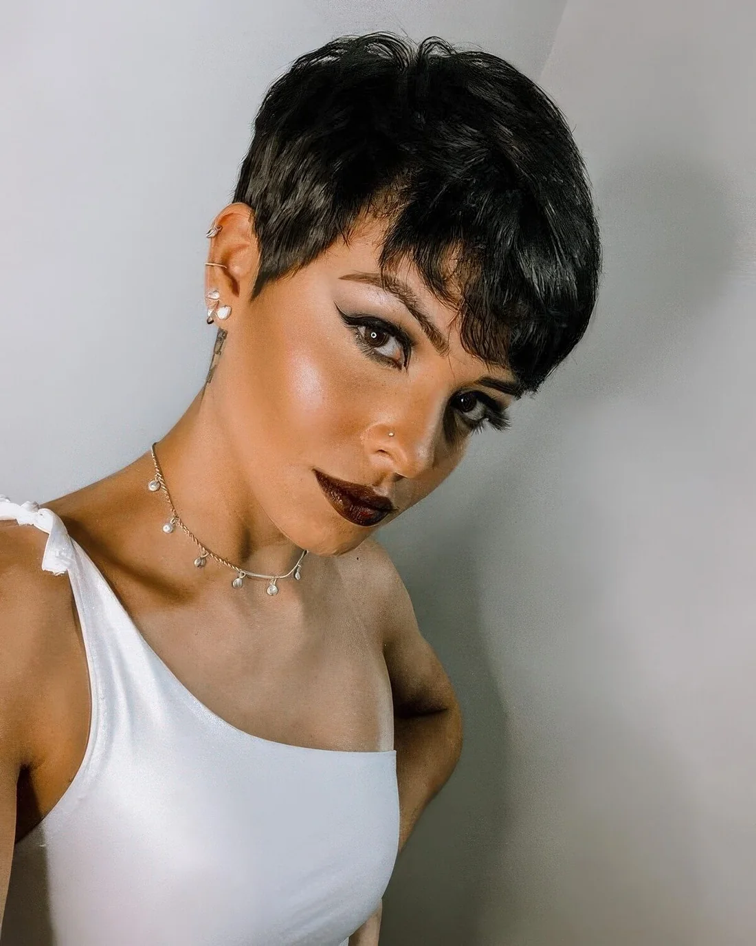 Black pixie haircut with side bangs and a lot of volume.