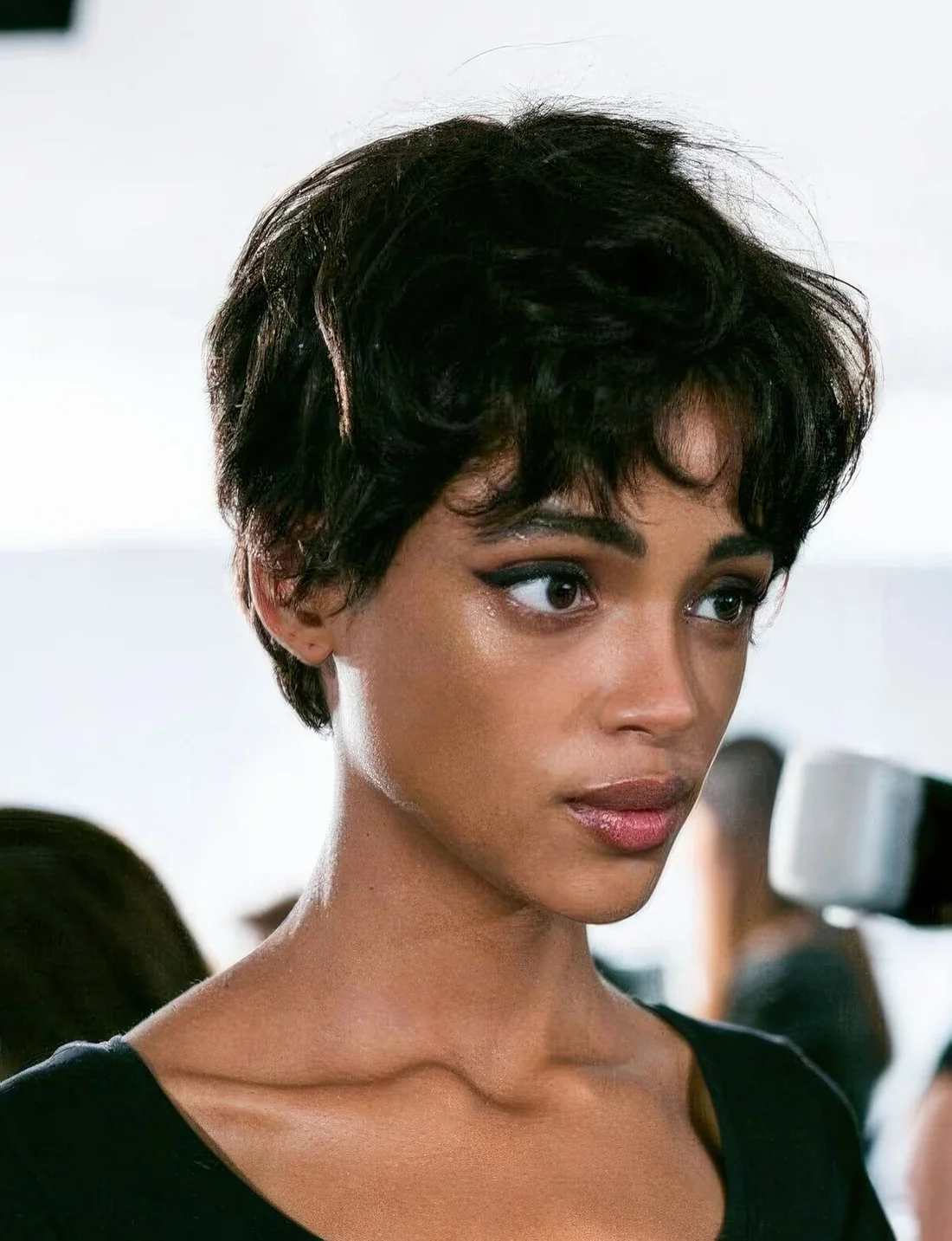 Messy and shaggy black pixie haircut with bottleneck bangs and slight waves.
