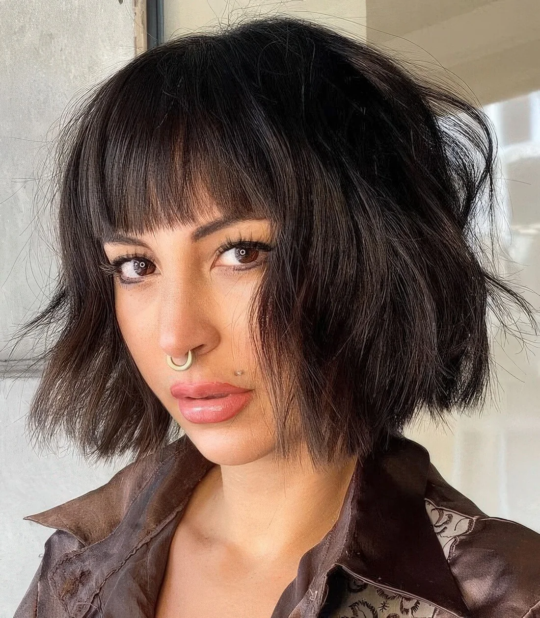 Black textural and wavy chin-length bob with waves and blunt bangs.
