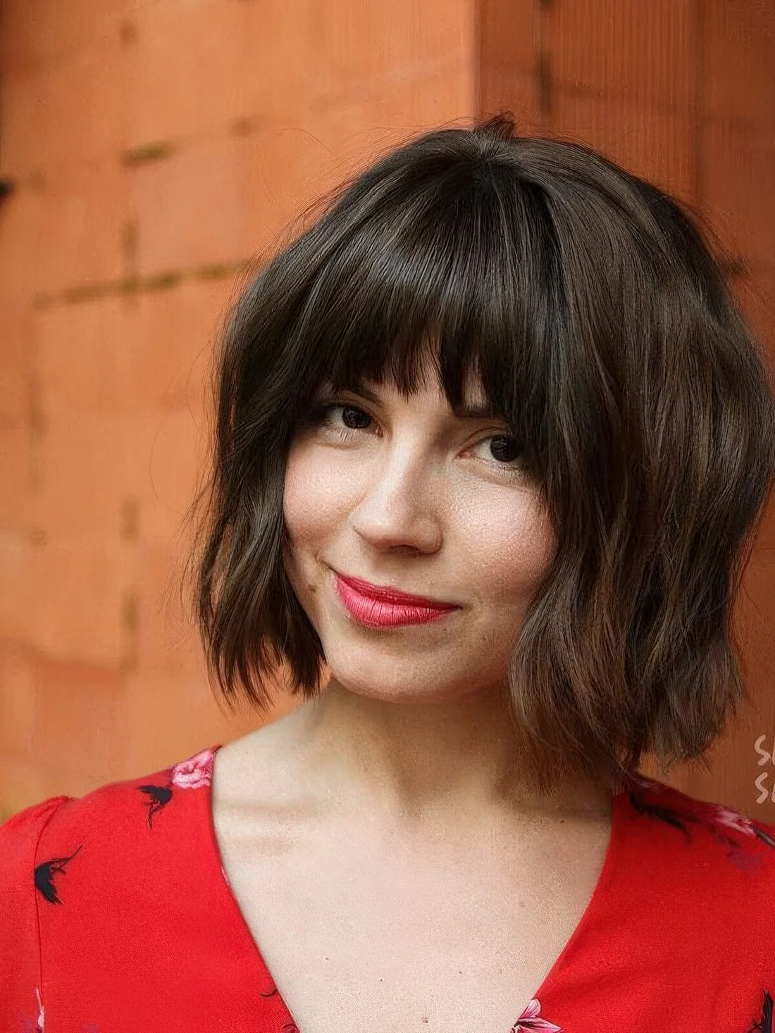 Dark brown chin-length bob with caramel highlights and blunt bangs.