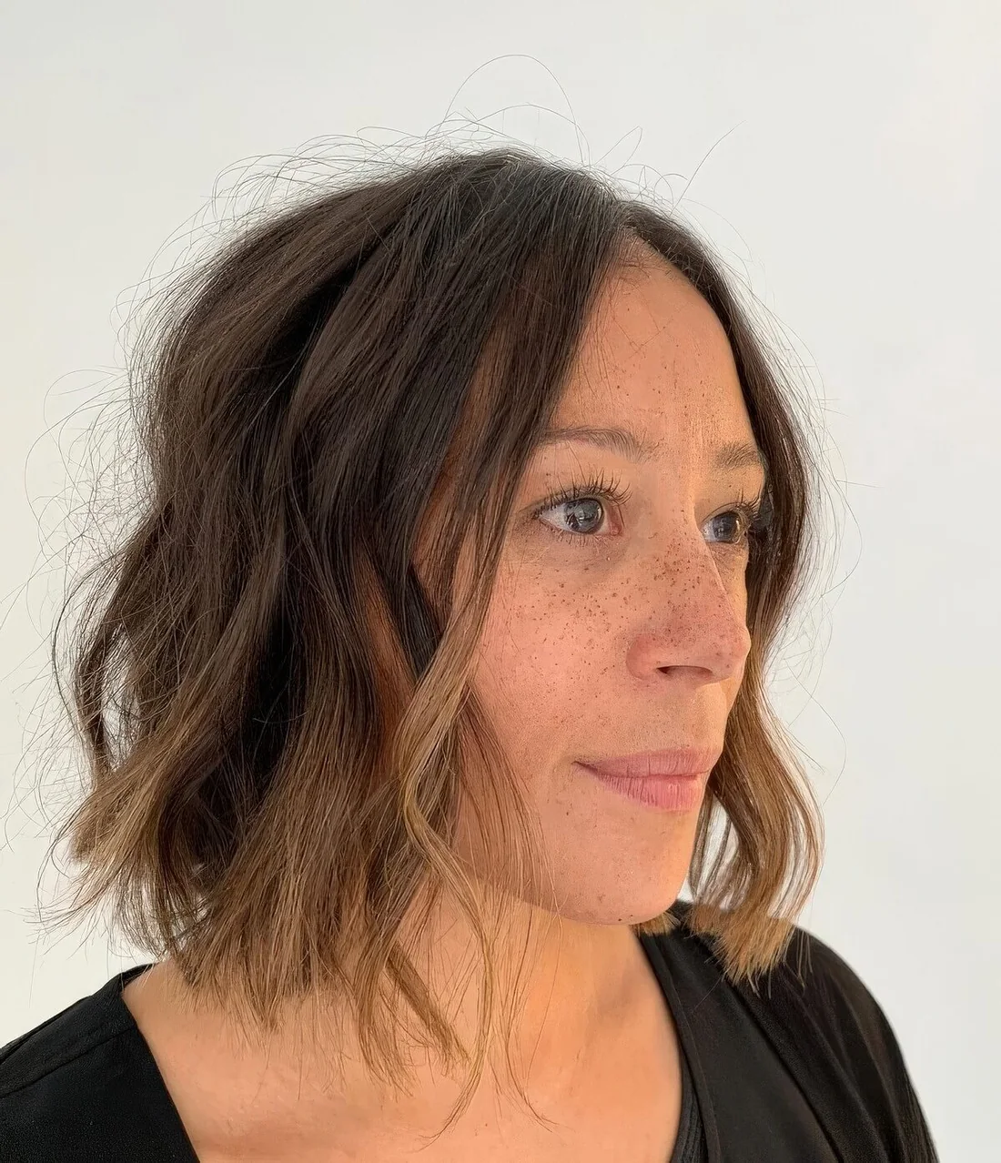 Wavy dark brown chin-length bob with caramel highlights.