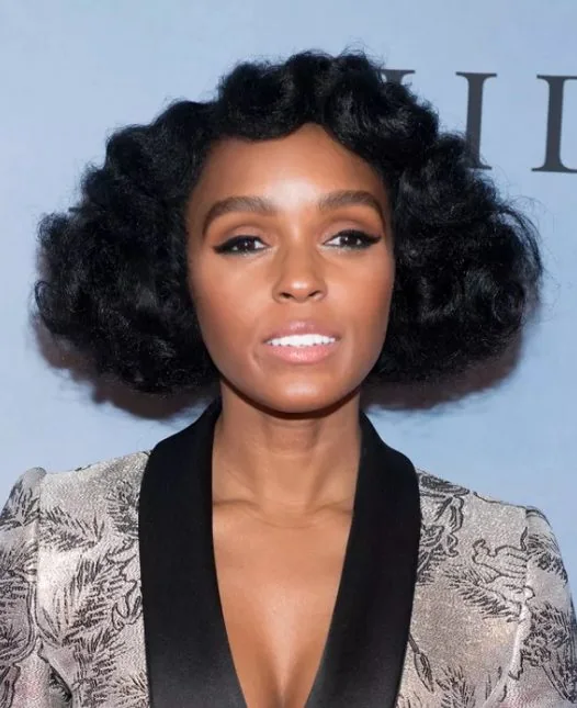 Janelle Monae's fluffy waves have a vintage pin curl effect, there are soft waves rippling over her forehead, and the round, cloud like shape the hair takes as it moves out from her head.