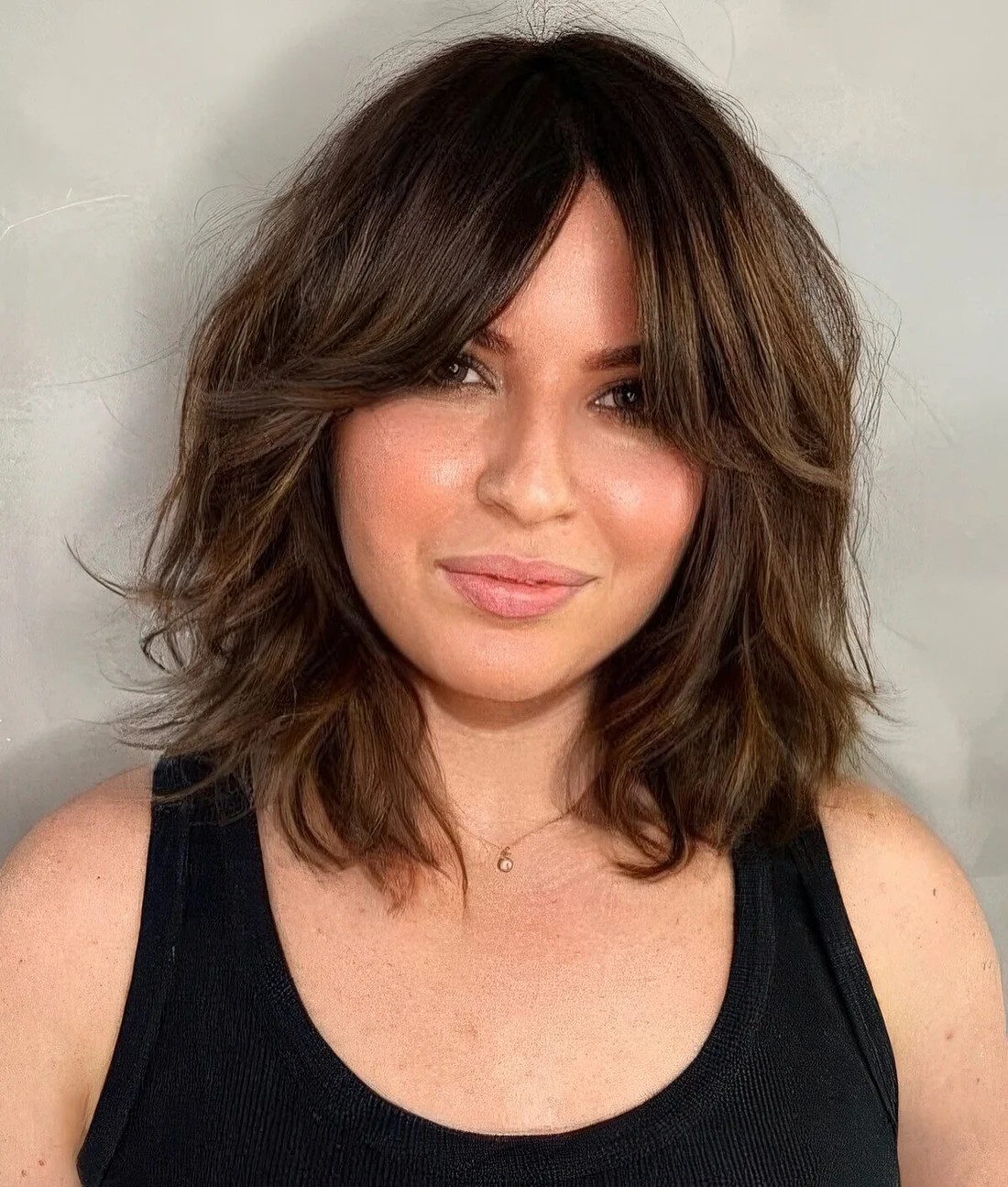 Dark brunette long bob with waves and bottleneck bangs features dimension and.