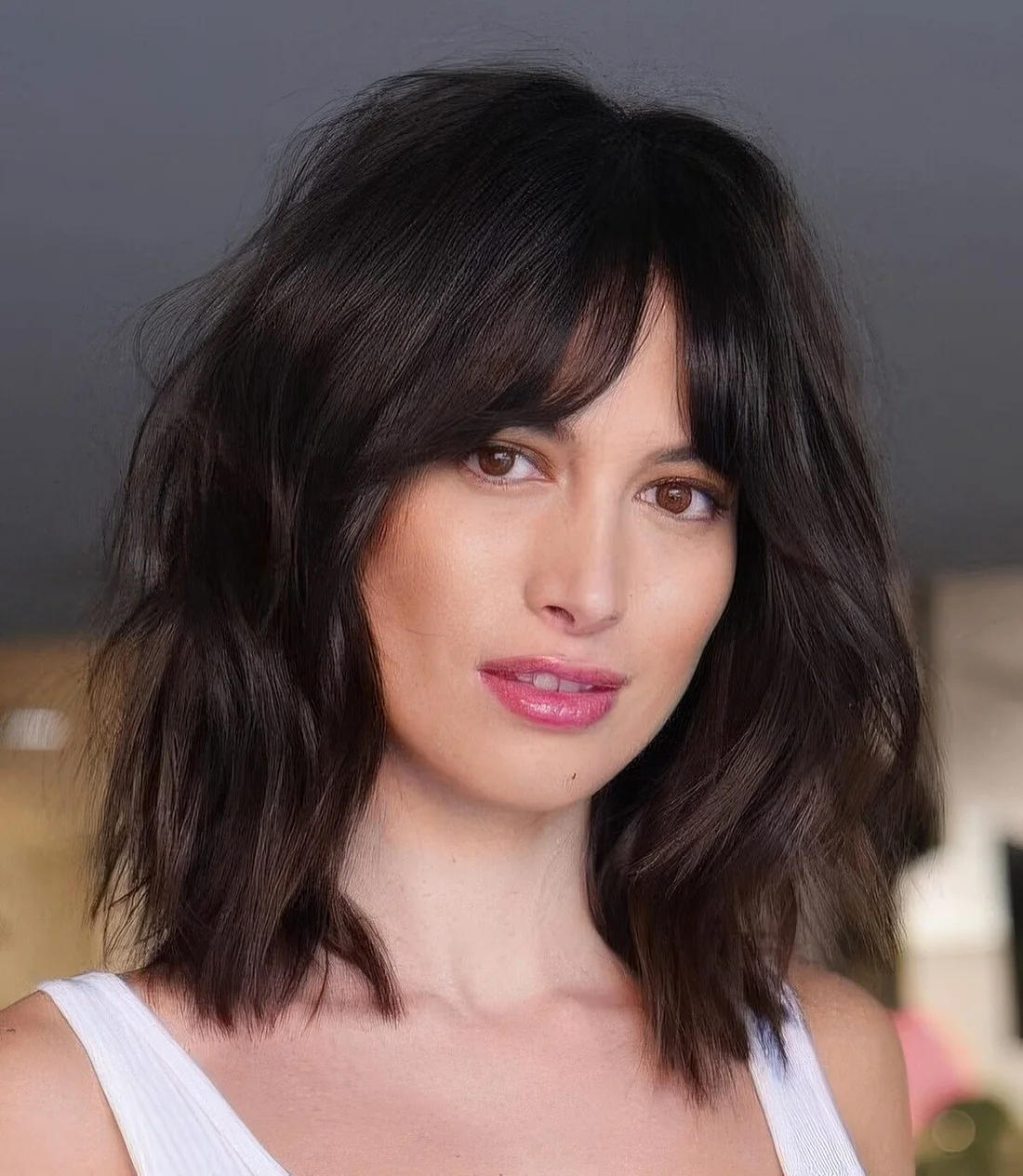 Black dimensional medium-length hairstyle with slight waves and bottleneck bangs.