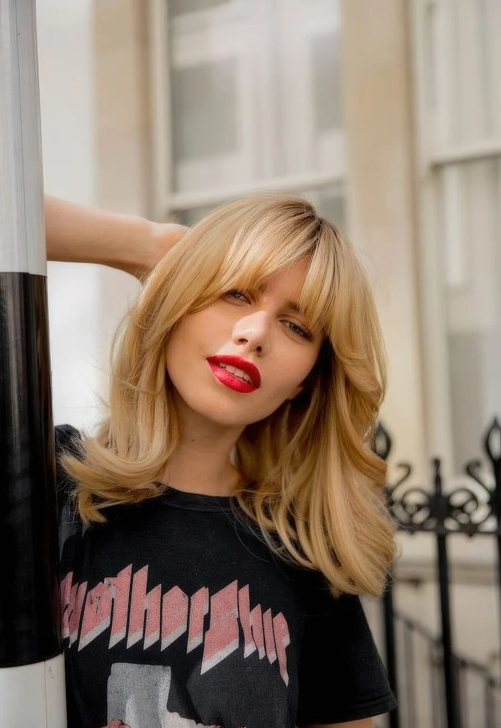 Medium blonde butterfly haircut with waves and bottleneck bangs.