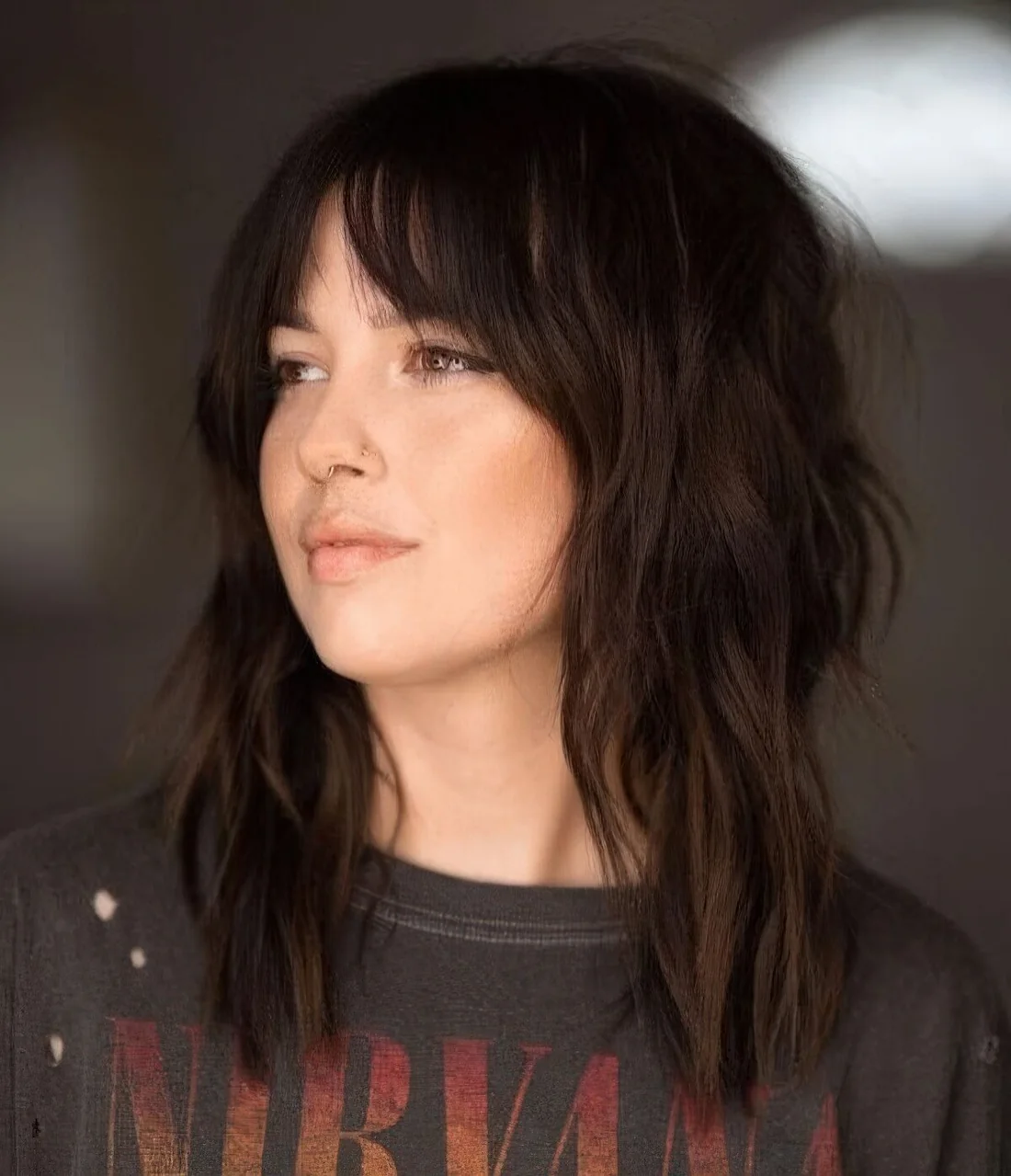 Dark brunette medium wolf cut with bottleneck bangs and messy waves.