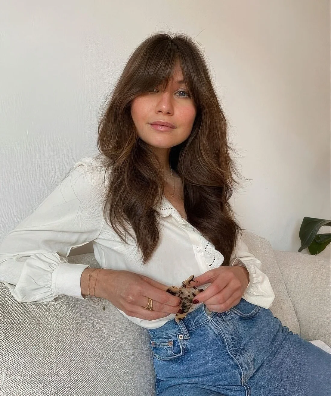 Long brunette butterfly haircut with bottleneck bangs and caramel balayage, volume and waves.