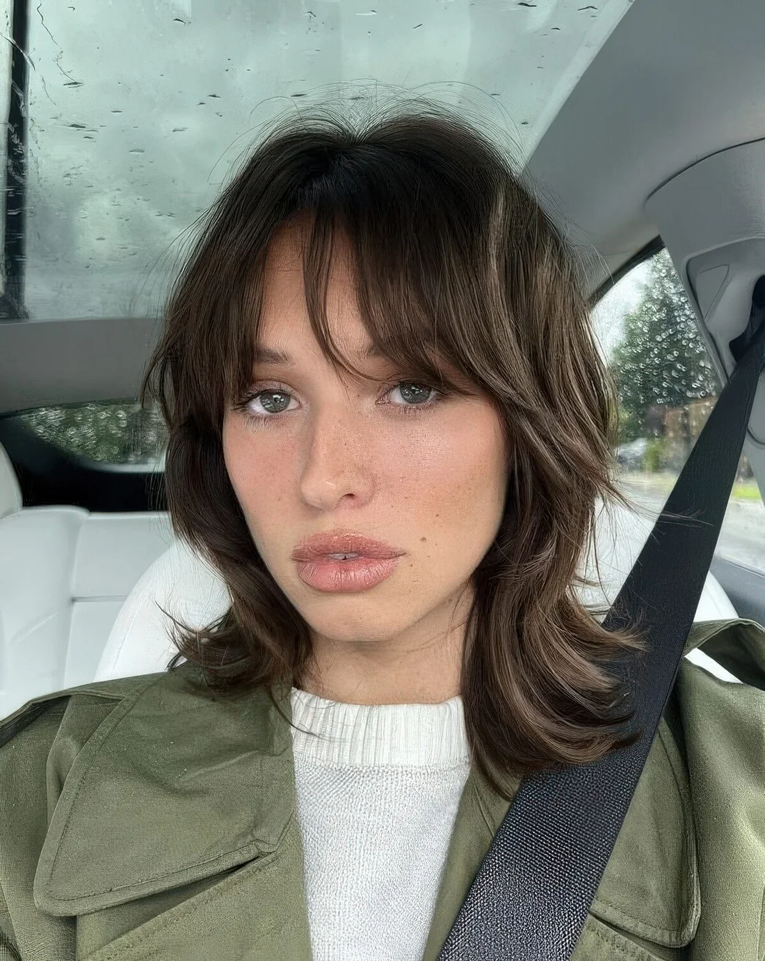 Medium-length wolf cut with bottleneck and wispy bangs, with curved ends.