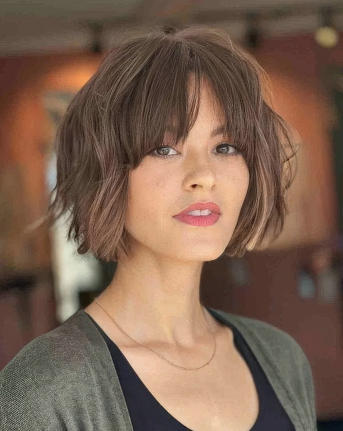 Messy brown chin-length bob with a bit of waves and bottleneck bangs plus highlights.