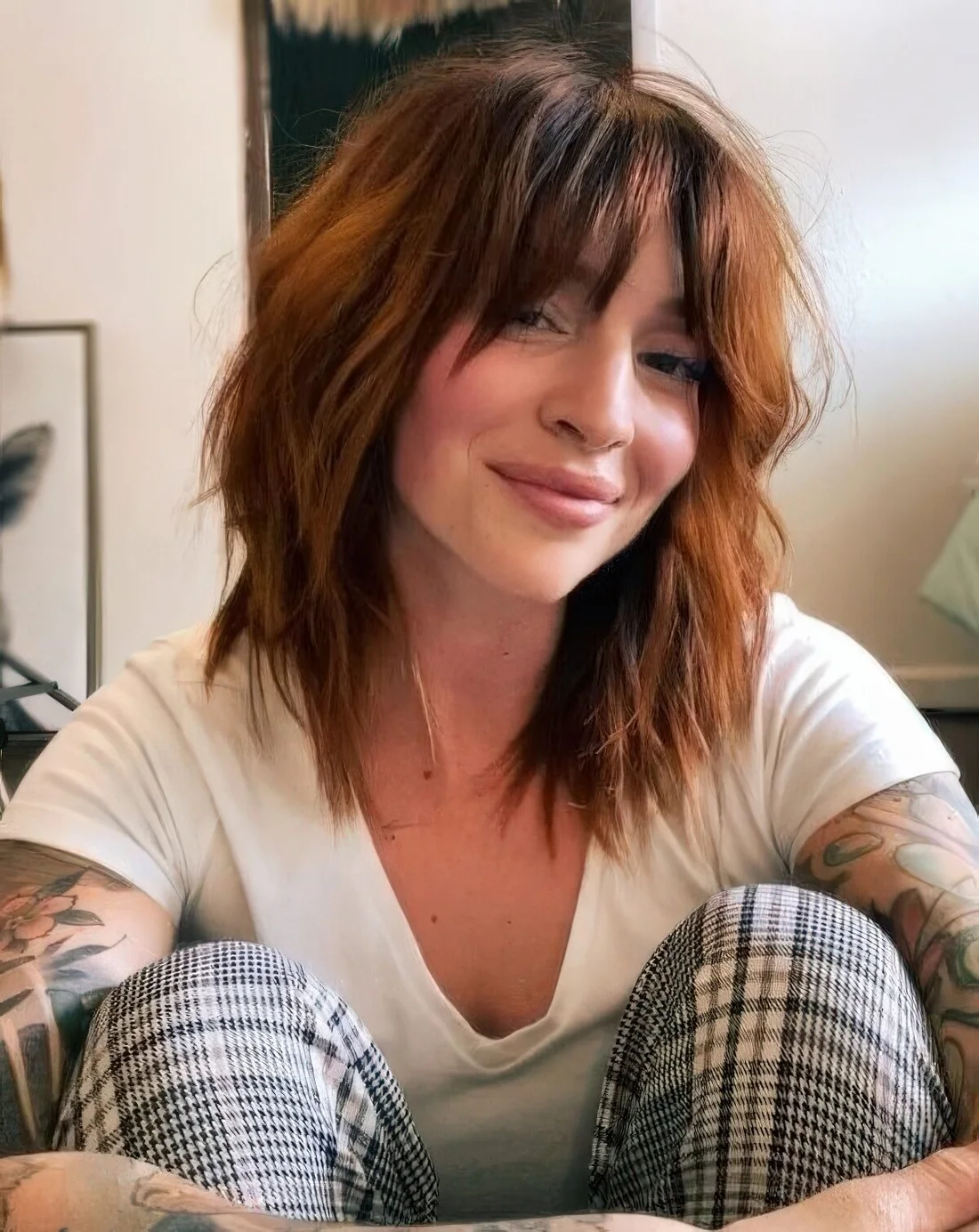 Shaggy medium-length copper haircut with messy waves and bottleneck bangs.