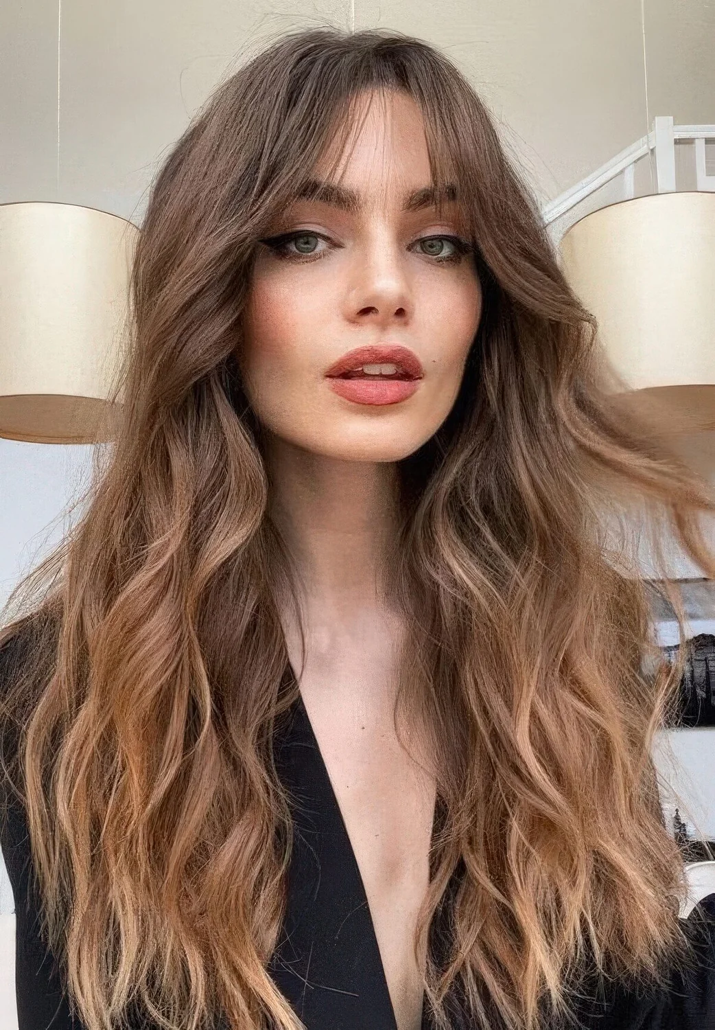 Long brunette hair with a slight ombre effect, bottleneck bangs and waves.