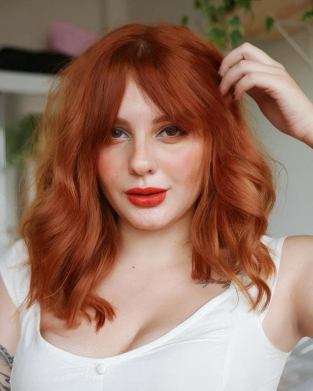 Ginger medium-length hair with bottleneck bangs and a lot of volume and waves.