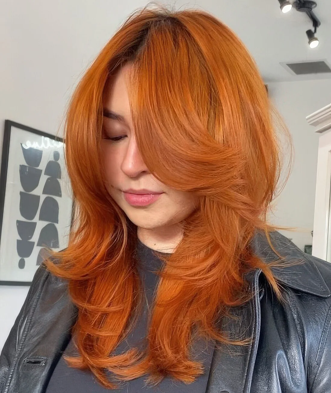 Ginger butterfly haircut of medium-length, with bottleneck bangs and curled ends.