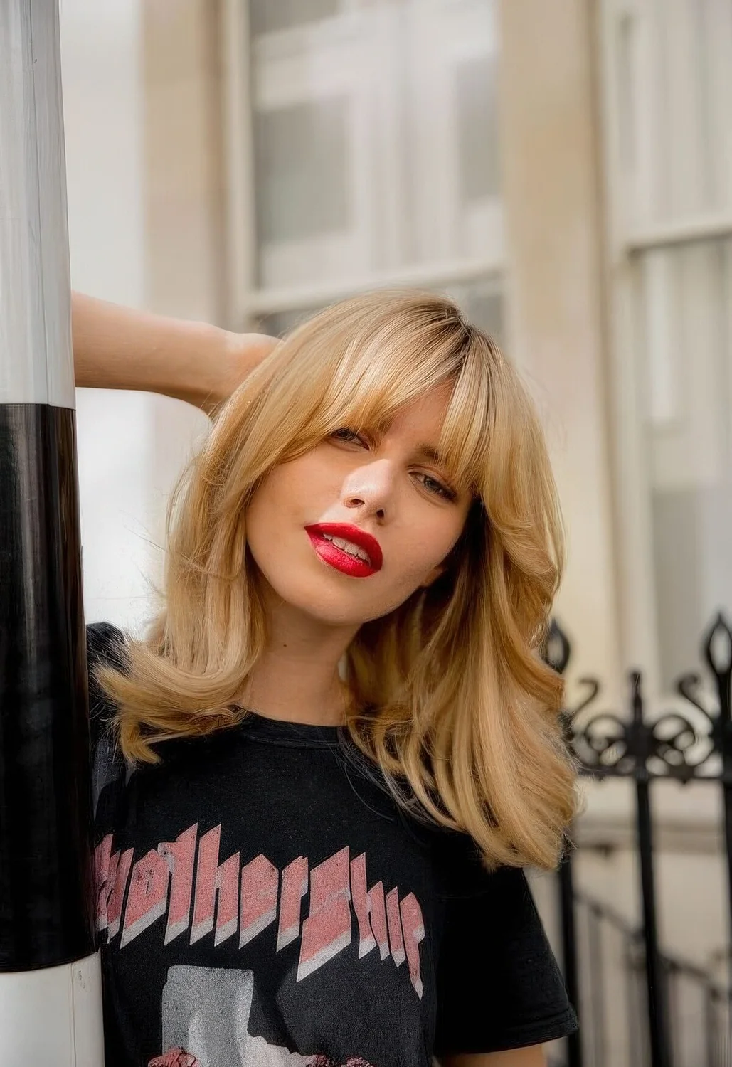 Medium blonde butterfly haircut with waves and bottleneck bangs.