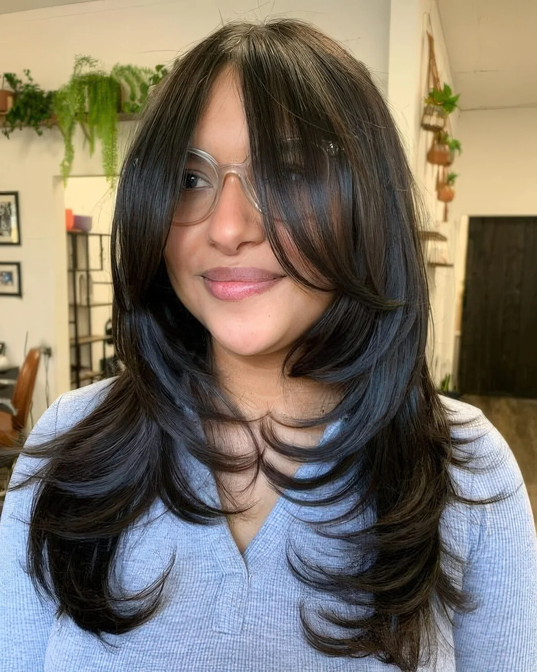 Long black butterfly haircut with bottleneck bangs and curled ends.