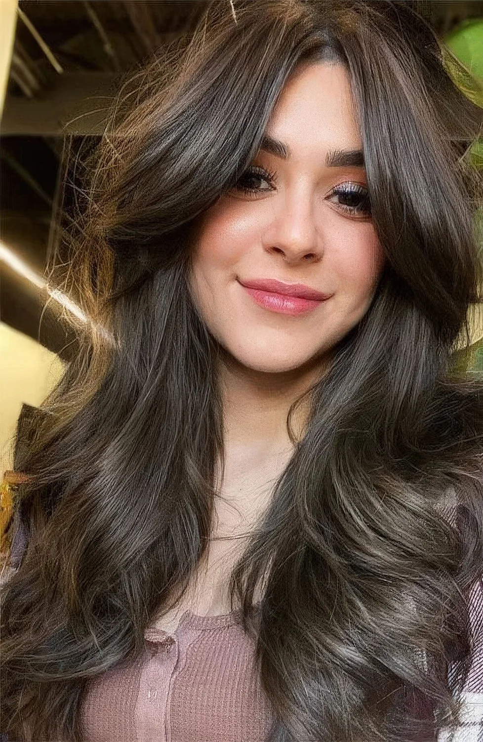 Long brunette butterfly hairstyle with bottleneck bangs and waves plus a lot of volume.