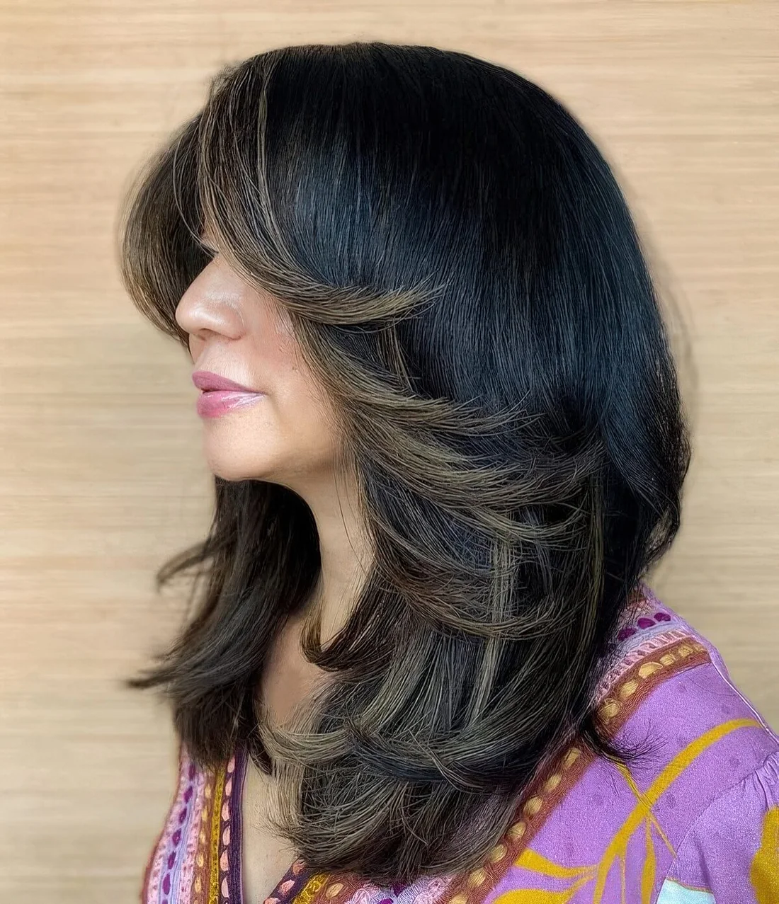 Medium black butterfly haircut with gold blonde curled ends and bottleneck bangs.