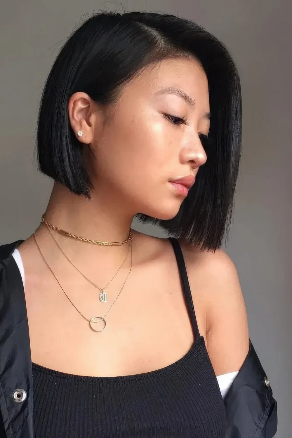 Black blunt bob with deep side part and straight hair.