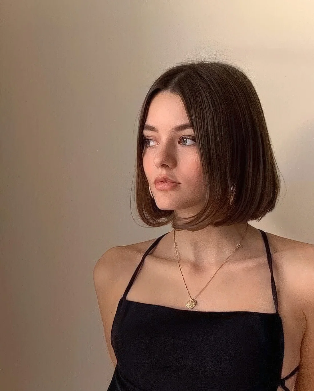 Box hairstyle with center part and curled ends.