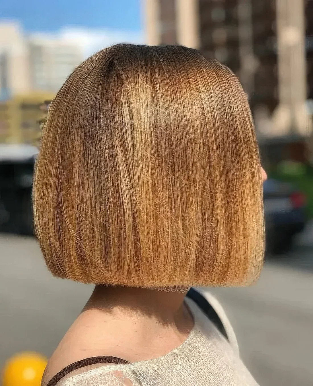 Honey blonde box hairstyle with a shiny touch and a darker root.