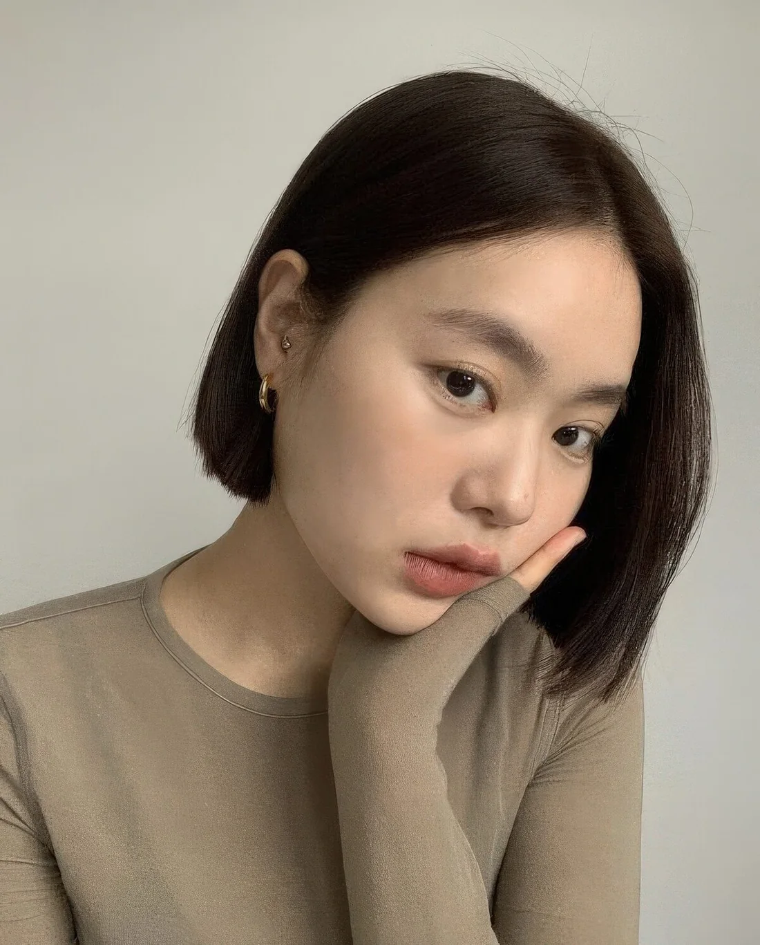 Sleek dark brunette chin-length bob with deep parting.