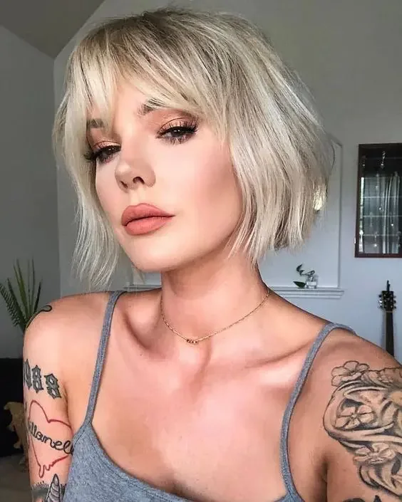 Col blonde boy bob with waves and bottleneck bangs.