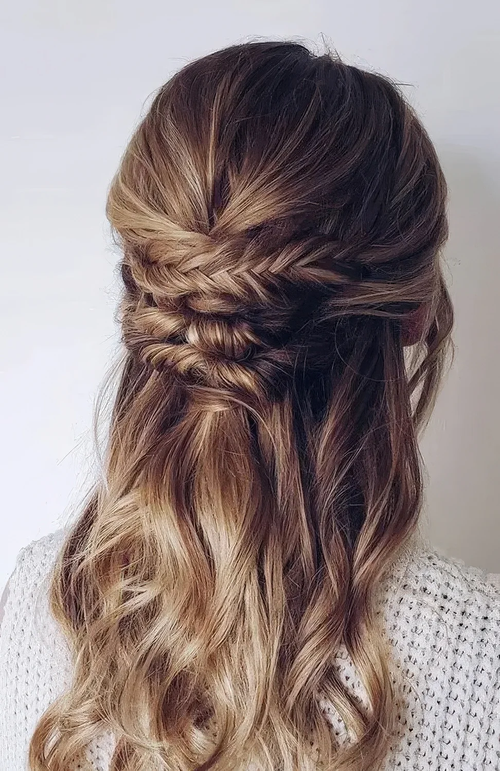 Boho half updo with a textured top and a braided and twisted element plus waves down.