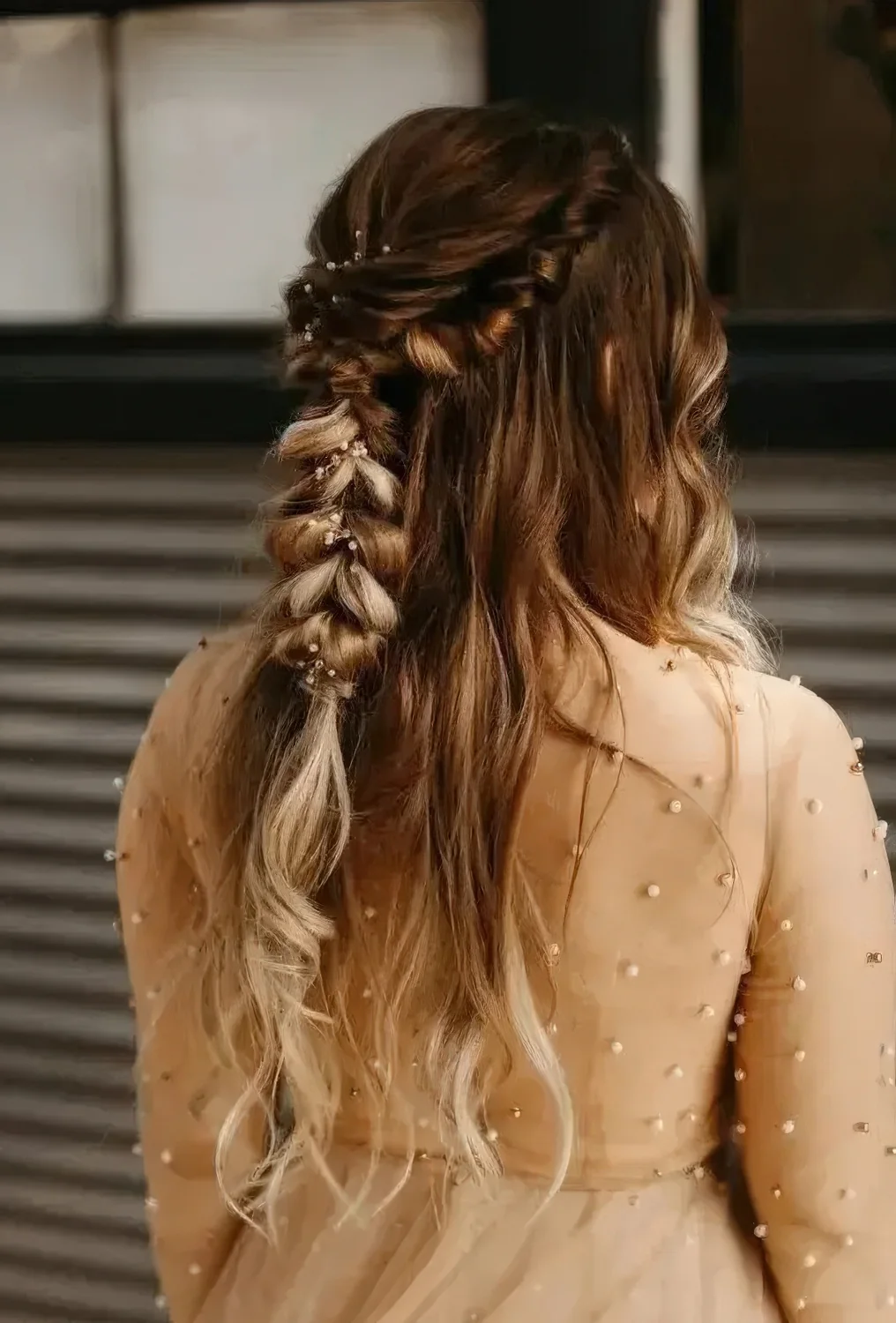 Wedding half updo with a twisted loose braid and waves down, with fresh blooms tucked in.