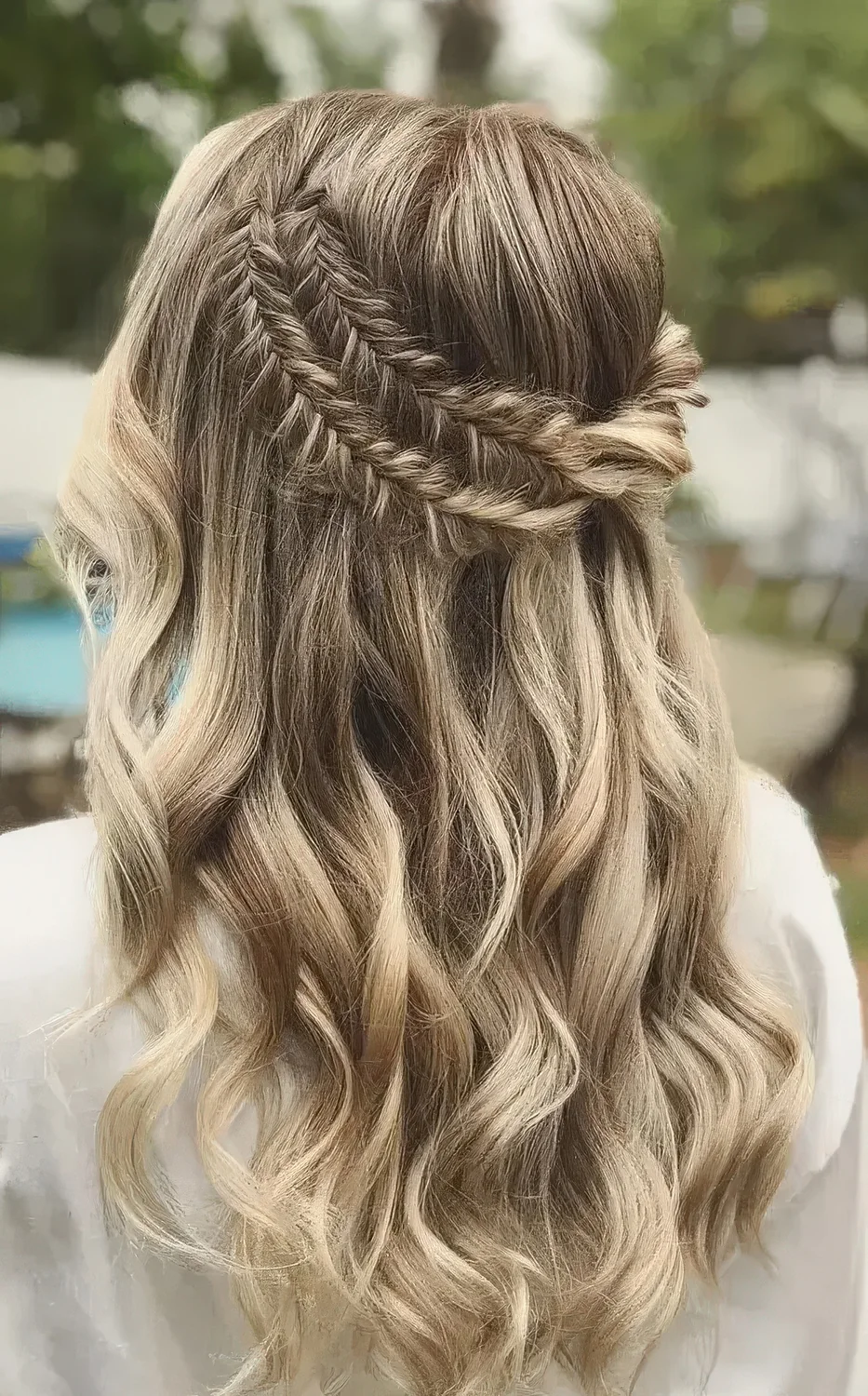 Boho half updo with a double fishtail braid halo and waves down.
