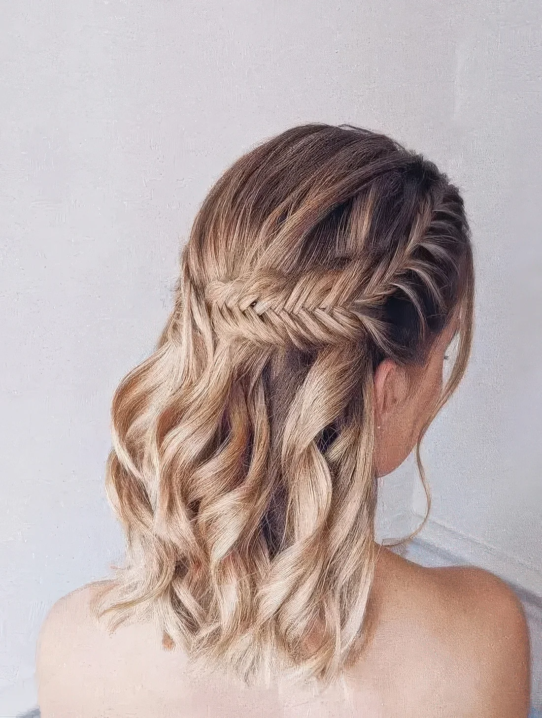 Boho wedding half updo on medium hair, with a large fishtail braid on one side and waves down.