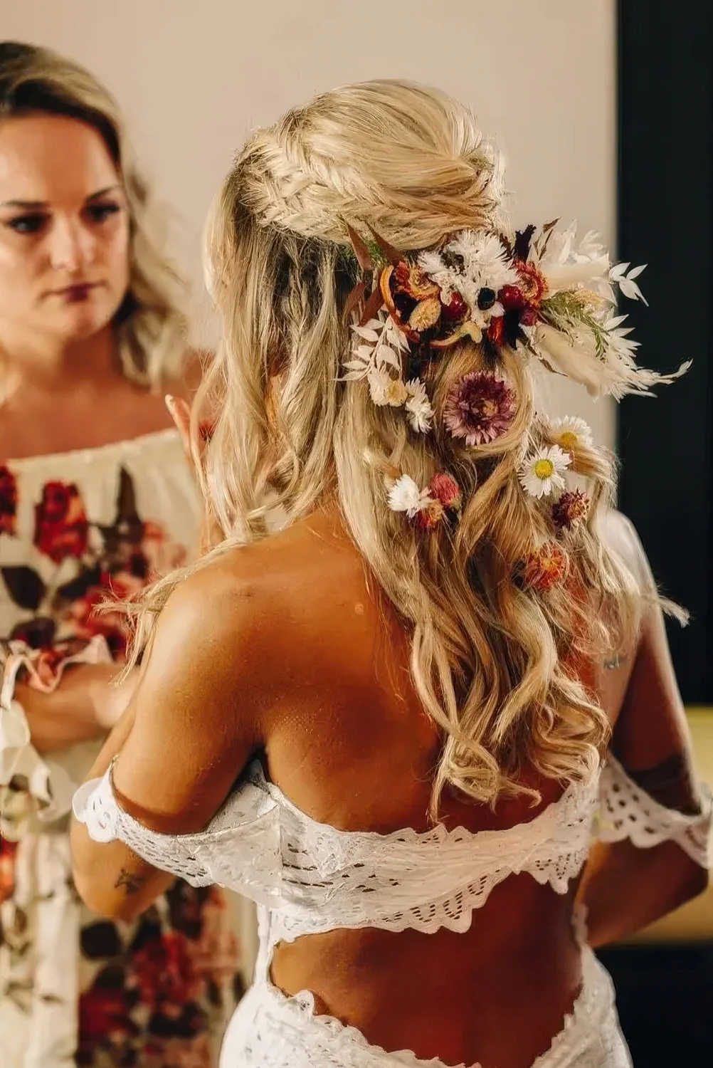 Boho wedding half updo with a double fishtail braid halo, waves down and a lot of dried blooms tucked in the hair.