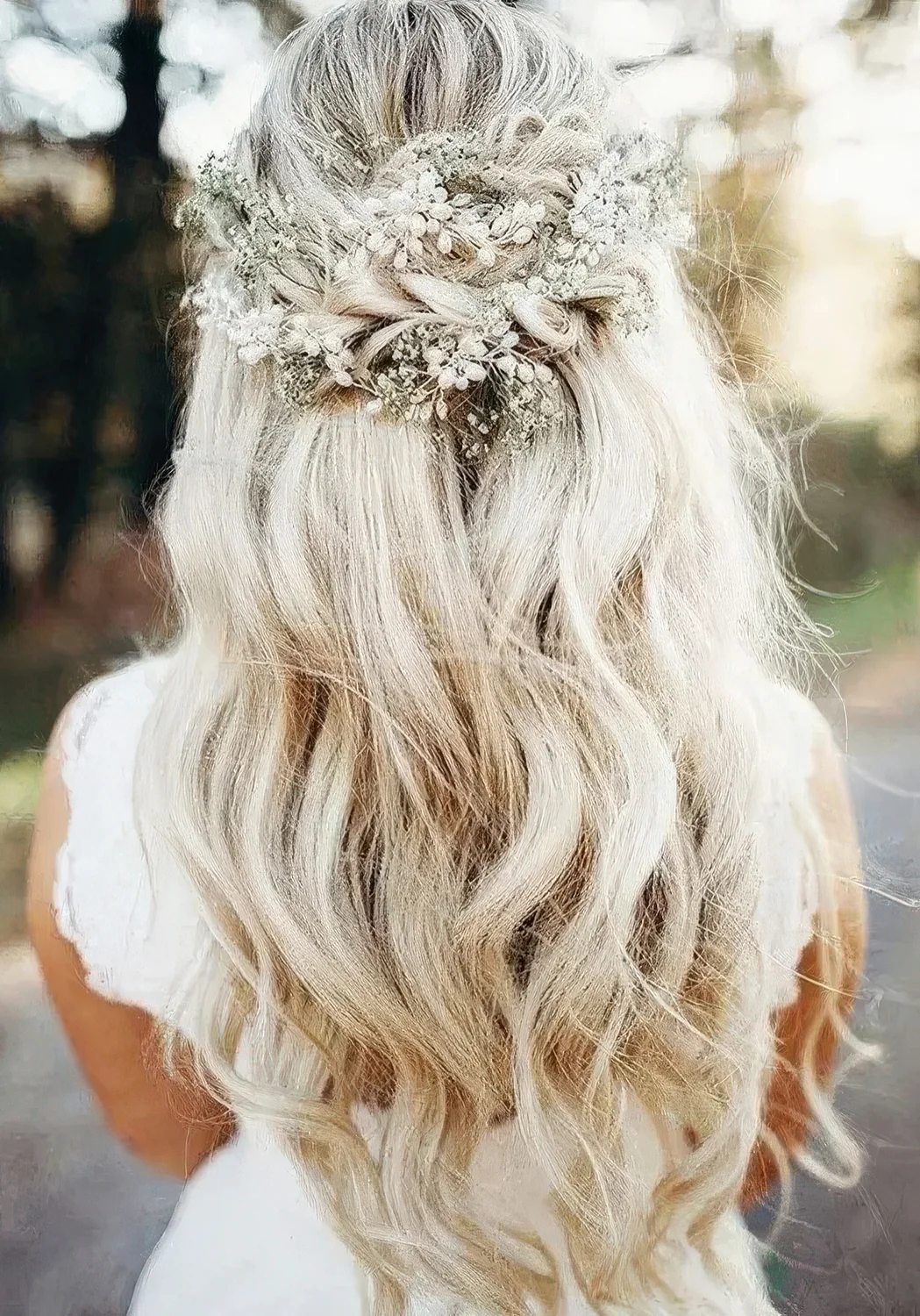 Boho wedding half updo with a volume on top, a braided part and waves down plus a pearl hairpiece and baby's breath.