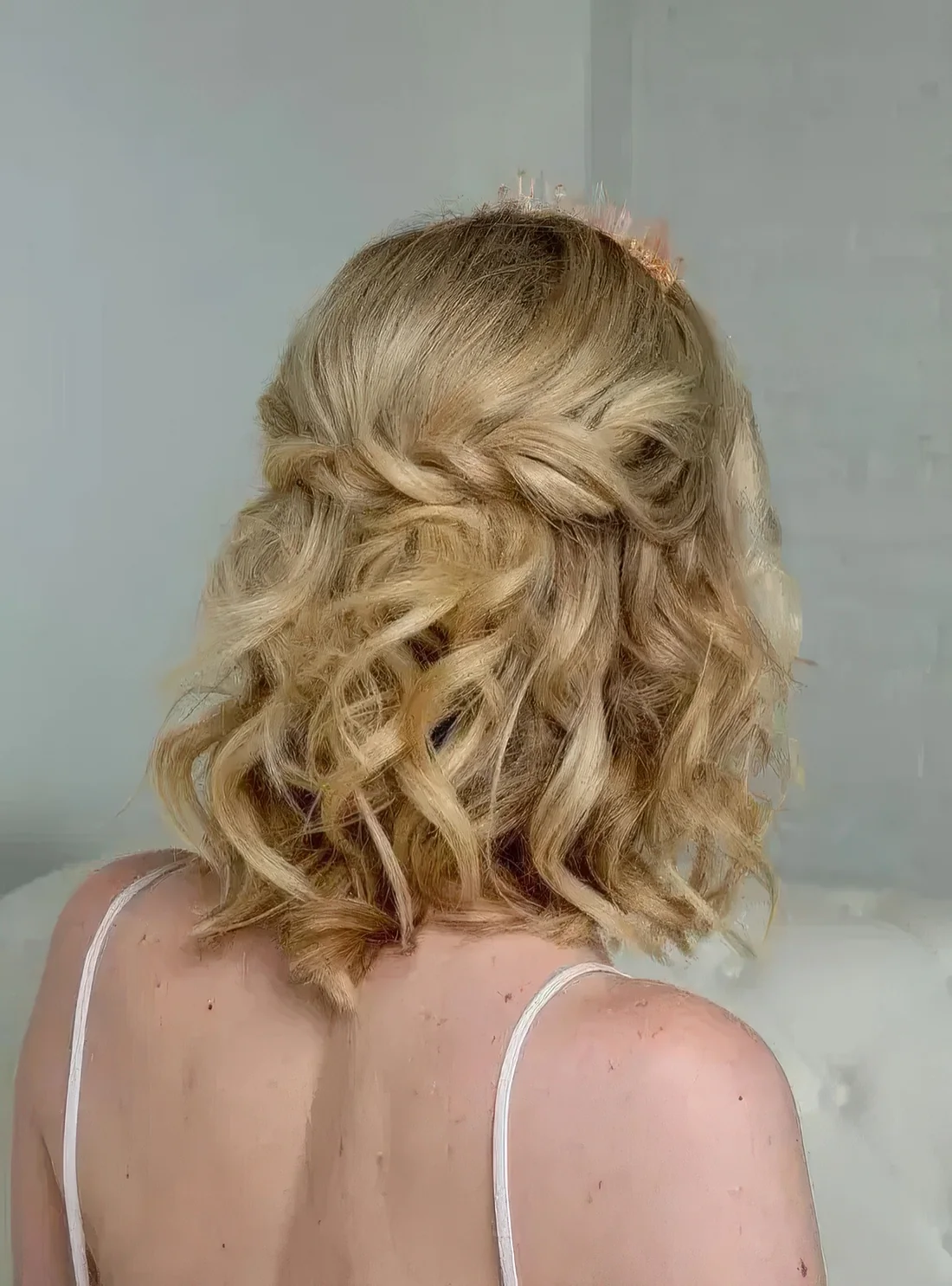 Curly half updo with a twisted braid and curls down plus a peachy crystal crown are a cool combo.