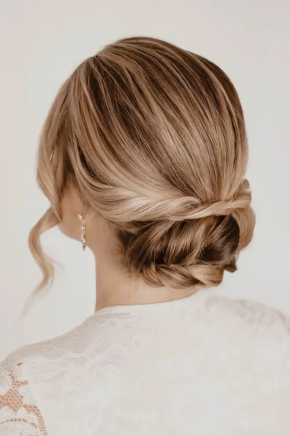 Laconic low updo with twists and a braid and a sleek top, waves framing the face.