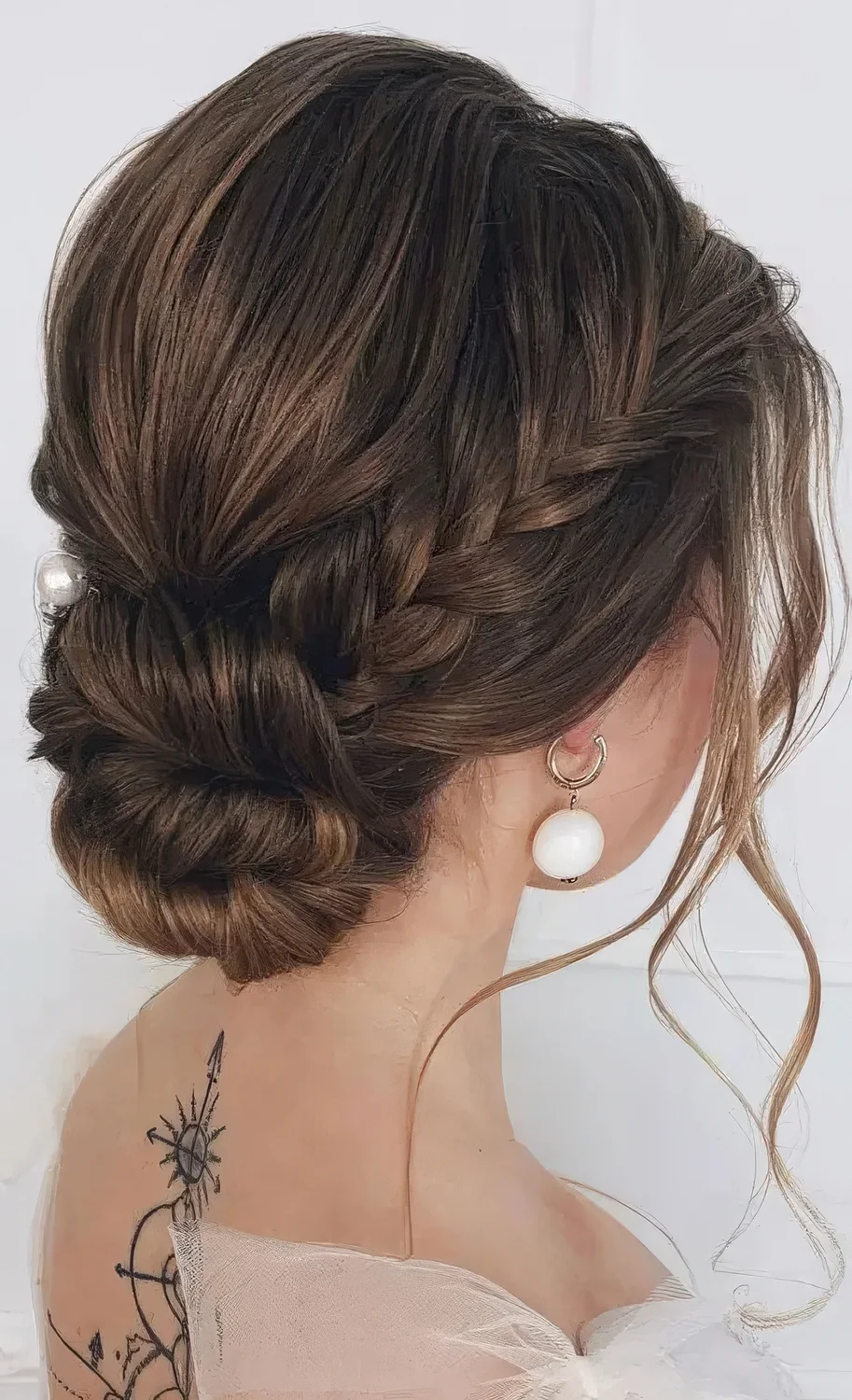 Twisted low updo with a braided halo, a bump on top and some locks framing the face.