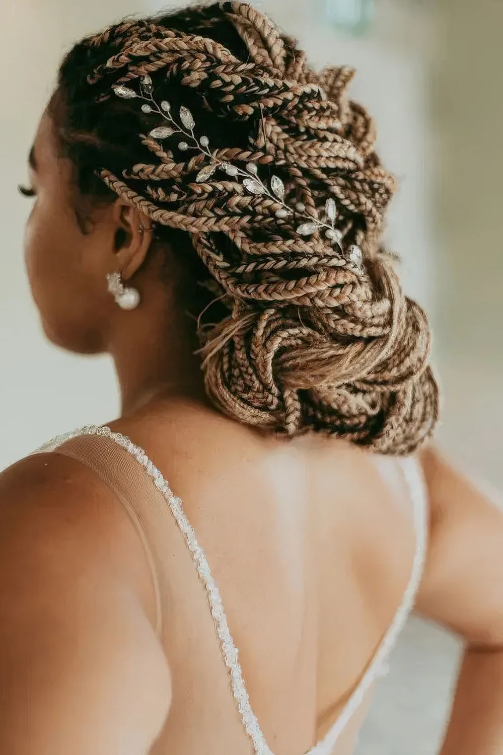 Fully braided low updo with a floral hair vine.