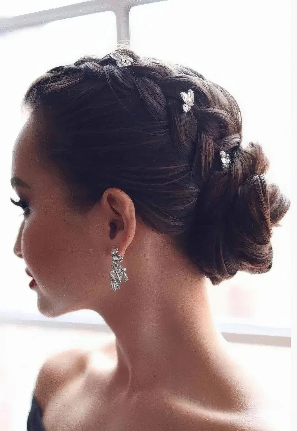 Glam updo with a braid on top and a low bun accented with rhinestone hairpins.