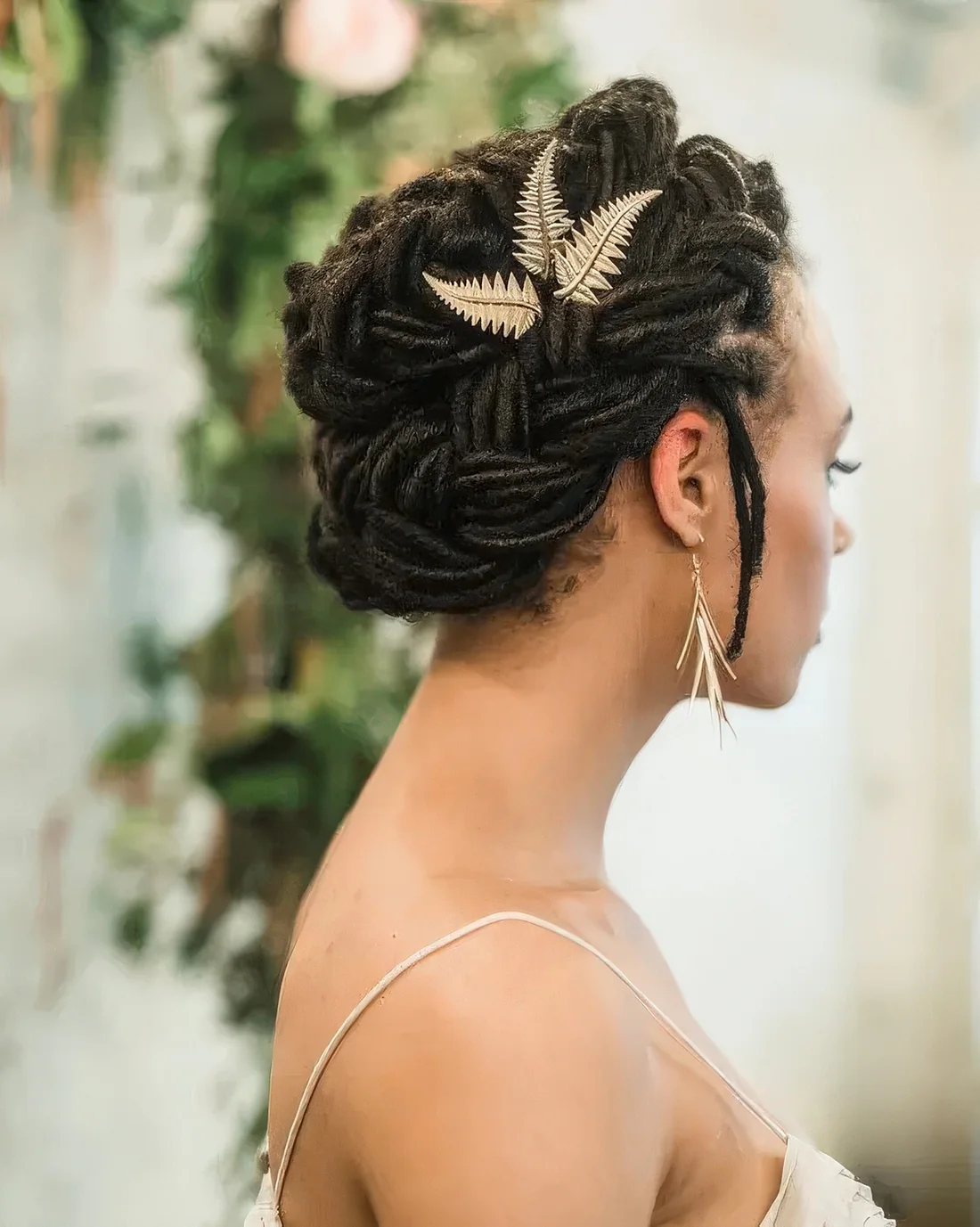 Braided updo with some locks down and gold leaf hair pieces.